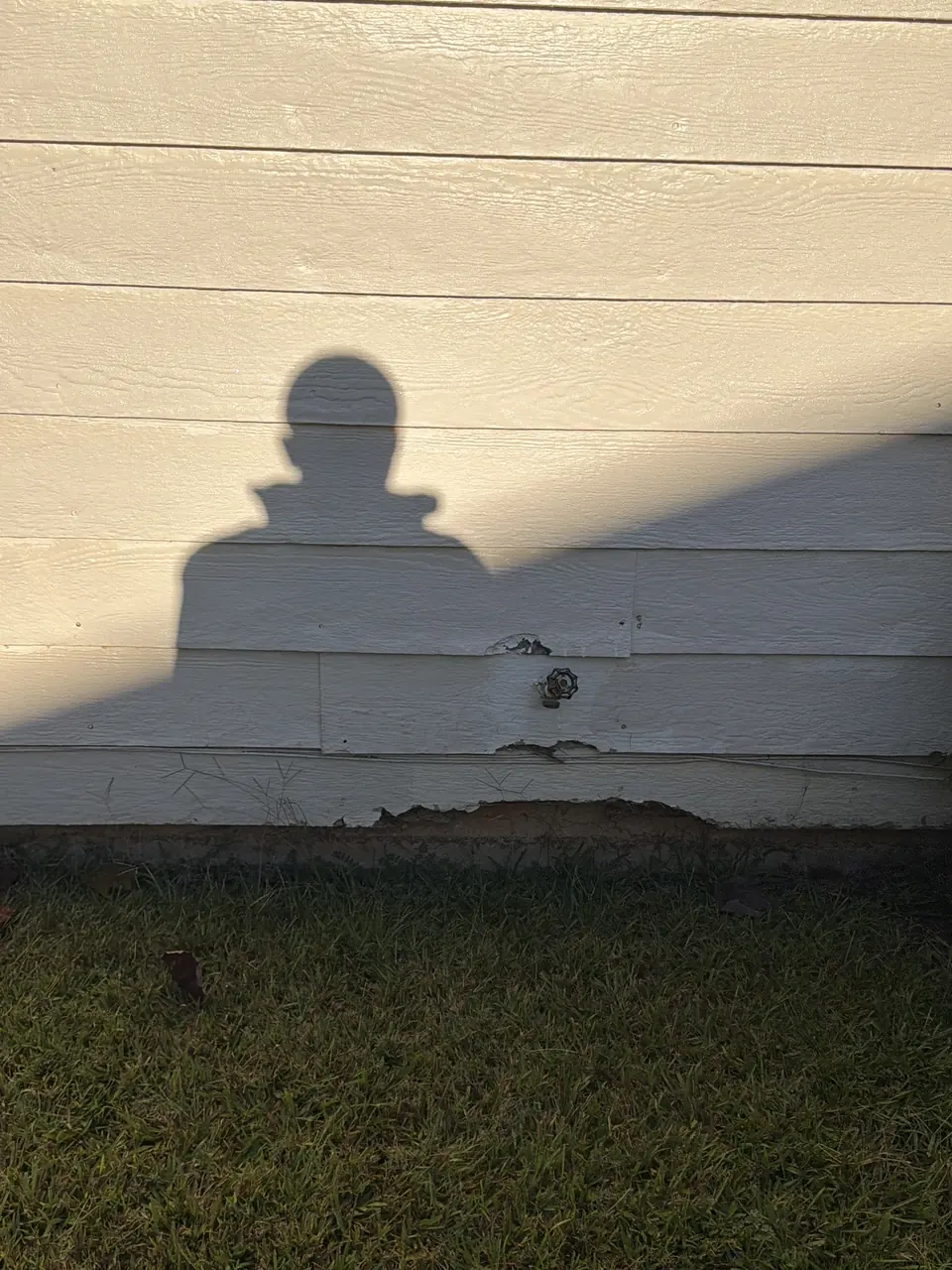 Damaged lap siding near grade at an exterior hose bib location
