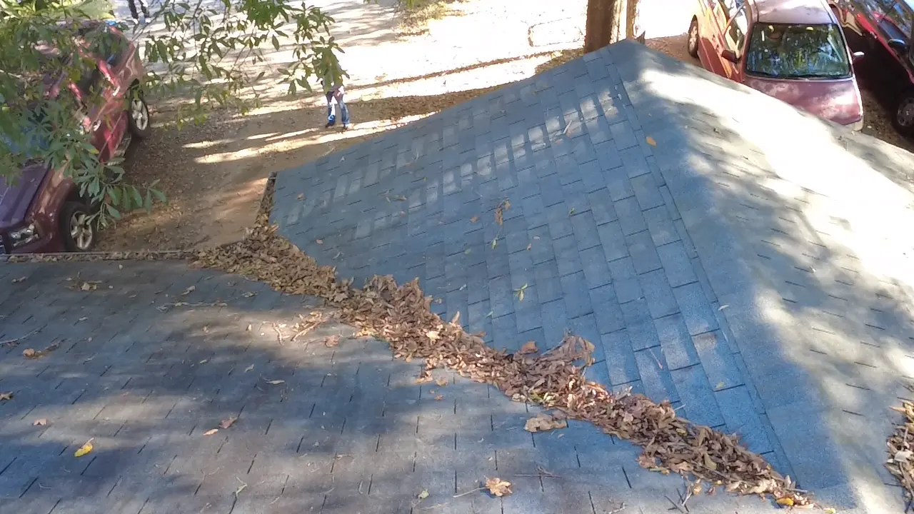 Drone photo of a roof valley holding leaf debris on an asphalt shingle roof