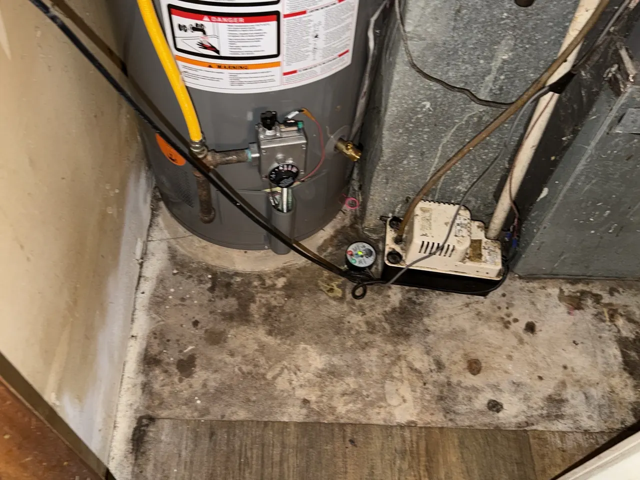 Gas water heater and pump unit in a mechanical area with moisture staining on the slab